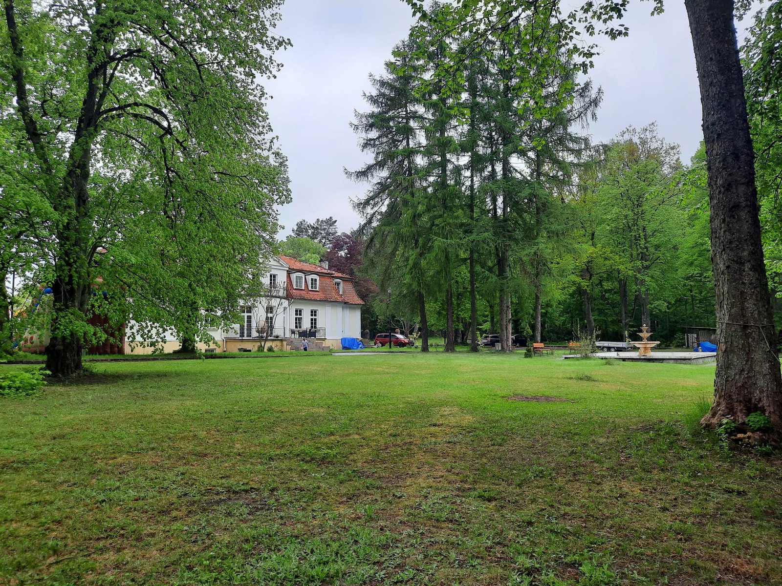 Rozległy park z widokiem na dworek i fontannę